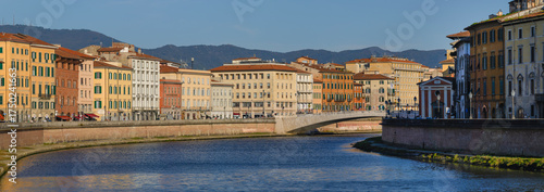 View of the Arno River with the Ponte di Mezzo bridge and pastel-colored buildings in the historic center of Pisa, Italy