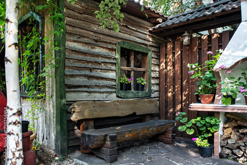 A wooden village house, a bench, flowers.