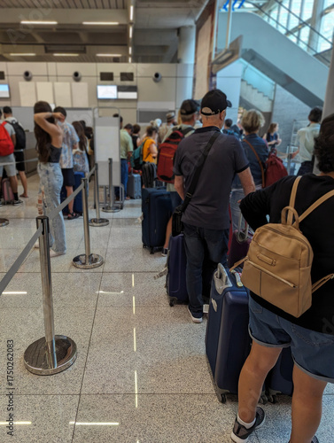 Travelers and passengers queue with luggage at airport check-in counters. People waiting with bags and suitcases, busy environment, flight and travel anticipation, terminal interior, pre-flight. 
