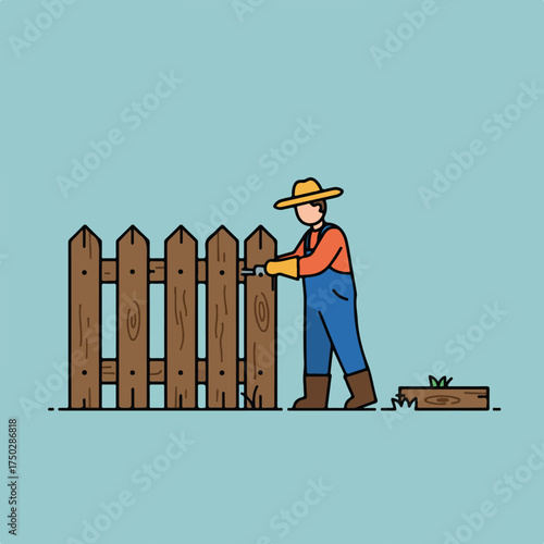 Person in blue overalls and hat repairs wooden fence with tool