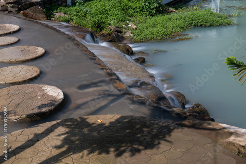 A peaceful view of cascading water and round concrete stepping stones at De'camp Hill Ka-ang resort in Nakhon Nayok, Thailand.