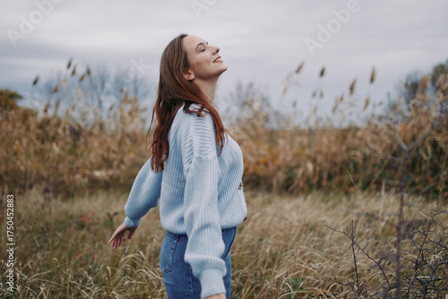 Tableau sur toile Young woman breathes deeply in a windswept field, a candid natural pose conveying genuine, authentic emotion and a trustworthy connection with nature and self under soft overcast light
