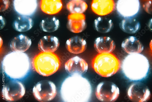A close-up view of colorful LED lights glowing in a grid pattern, blending warm orange and cool white tones.