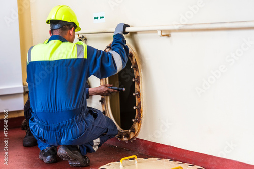 Carta da parati Crew member near a narrow hatch after providing first aid during a man evacuation drill from a confined space on a merchant ship