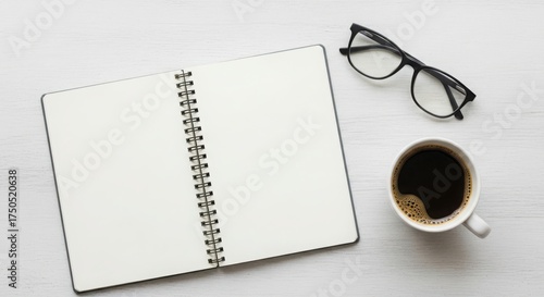 Open notebook, eyeglasses, and a cup of coffee on a white wooden table, top view