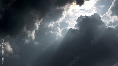Beam of sunlight breaking through dark storm clouds, illuminating the ground.