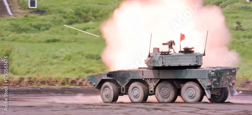 The robust eight wheeled vehicle generates a dramatic muzzle flash during a live fire exercise at the outdoor range, showcasing its formidable firepower in a dynamic moment.