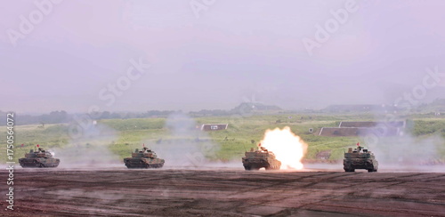 Armored vehicles engage targets on a vast military range, demonstrating intense combat readiness and precision gunnery in challenging conditions.