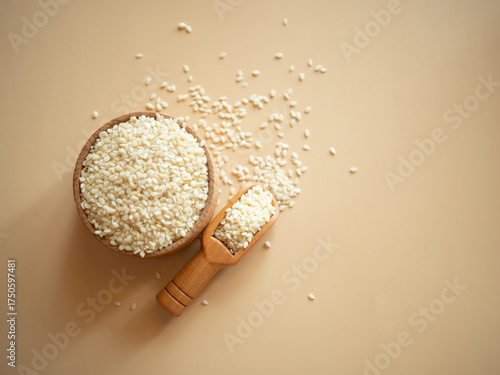 sesame seeds in a wooden bowl on a beige background