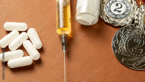 Syringes, medals, and pills on background represent doping in sports. The use of anabolic steroids by athletes for performance enhancement is a form of sports fraud. Doping is a serious issue that