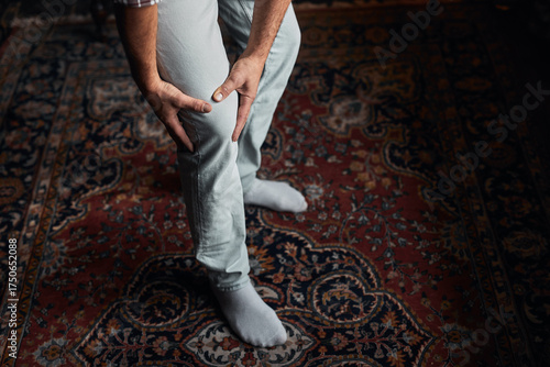 Foto Man at home holding painful injured knee.