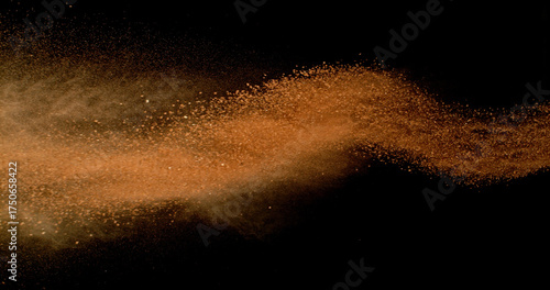 Fotografie Flying orange clay dust in motion, isolated on black background
