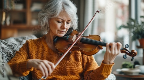 An elderly woman plays the violin in a cozy home setting, useful for illustrations about hobbies and creativity in old age.