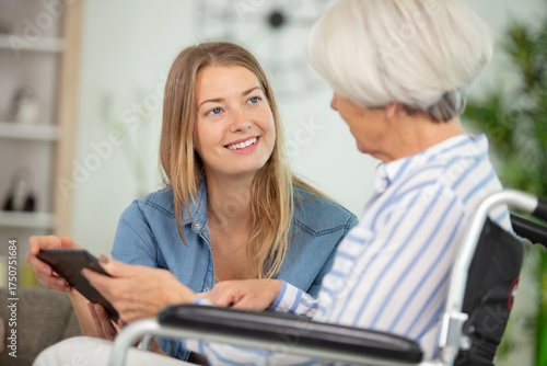 cheerful woman taking care of her grandmother in wheelchair