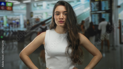 Free Download Tall woman in white sleeveless top points finger at camera in busy airport terminal; warning authority caution. - GFXLoad
