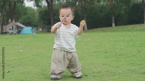 Asian babies playing with sticks on the grass in the morning, babies learning to walk