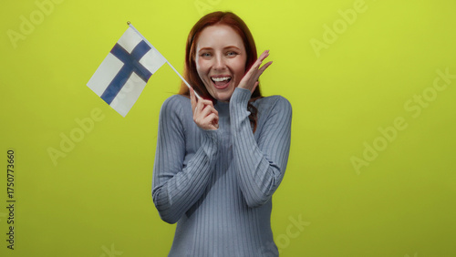 Quadro su tela Woman holding finnish flag cheerfully against vibrant yellow background, embodying national pride and joyful expression