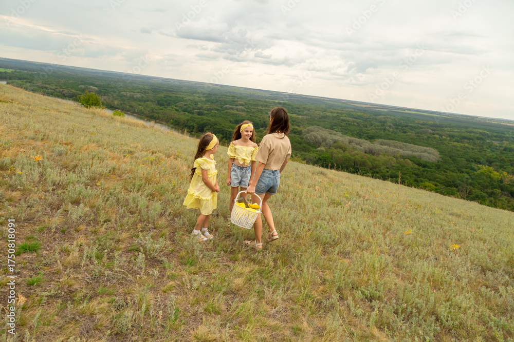 Obraz premium Family on a meadow, mother and daughter holding hands while carries picnic basket