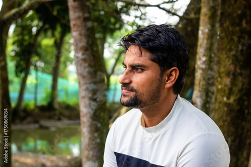 Contemplative young man enjoys peaceful nature retreat, finding serenity and inspiration amongst the trees, a moment of reflection in a verdant forest setting