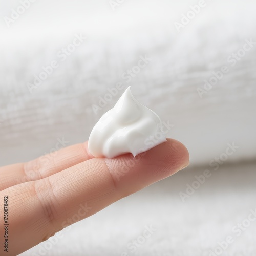 Close up of white skincare cream dollop on a finger.