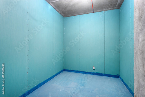 An empty room with waterproofed walls and floor before tiling.