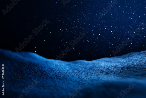 A close-up of a textured blue surface resembling a snowy landscape under a starry night sky filled with numerous small bright stars