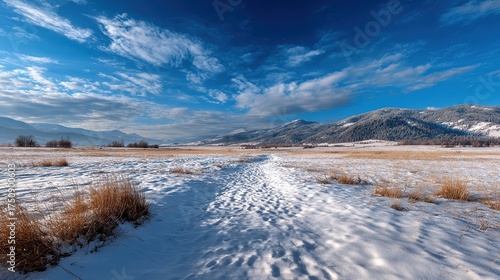 Snowy winter landscape with a lake reflecting the mountains under a cloudy sky