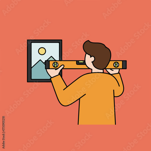 Man uses a level to hang a framed mountain landscape on a salmon-colored wall