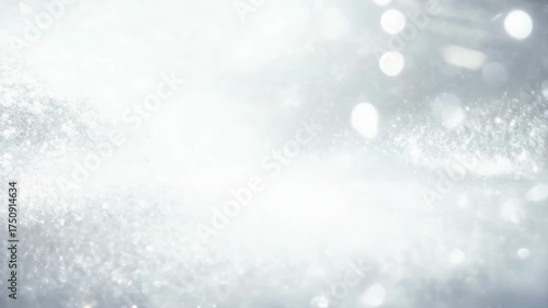 Abstract shimmering particles drift across a bright white and silver background with soft bokeh lights creating a gentle festive atmosphere