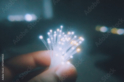 hand holds glowing fibers, illuminating dark space with vibrant