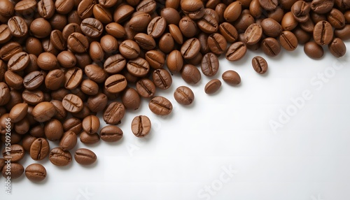 Roasted coffee beans scattered on a white surface, creating a diagonal pattern