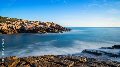 Rugged Coastal Cliffs Bathed in Golden Sunlight With Silky Smooth Blue Ocean Waves Under a Clear Sky