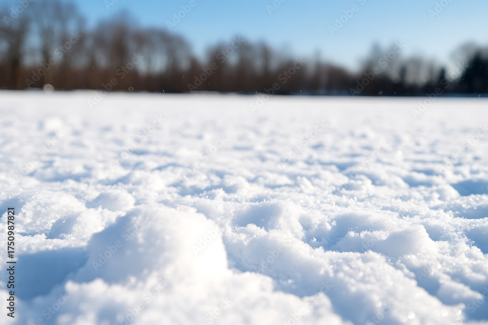 Fototapeta premium A pristine, snow-covered landscape gleams under a bright blue sky, creating a peaceful winter scene. The texture and depth of the snow invite quiet contemplation.