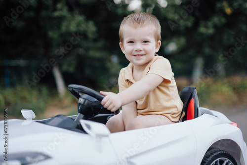 2 years boy riding electric car toy on the road with smile