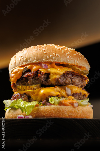 Close-up of a juicy double cheeseburger with melted cheese, lettuce, pickles, and onions on a sesame bun, captured on a dark background