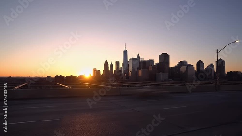 Majestic City Skyline at Sunrise With Warm Orange and Purple Hues Overlooking a Highway Overpass With Moving Vehicles and Streetlights Casting Subtle