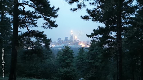 Majestic Cityscape Glimmering Through a Dense Forest Canopy At Dusk Featuring Tall Pine Trees and Distant Illuminated Skyscrapers Under a Hazy Blue