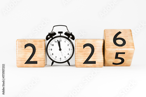 Wooden blocks showing the numbers 2025-2026 placed in front of a clock