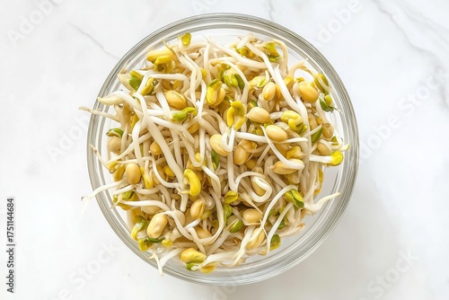 Fresh soybean sprouts in glass bowl on marble counter with bright natural lighting