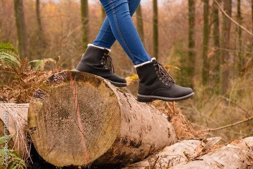 Walking on fallen tree trunk in autumn forest with black boots