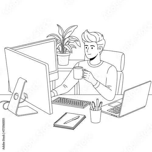 Young man sitting at a desk with a computer and laptop, holding a mug and looking at the screen
