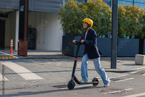 Young woman rides electric scooter on urban street wearing helmet