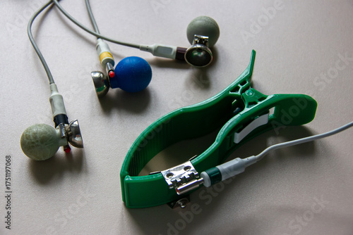 An electrode and a clamp for an electrocardiograph are on the table. On a gray background.