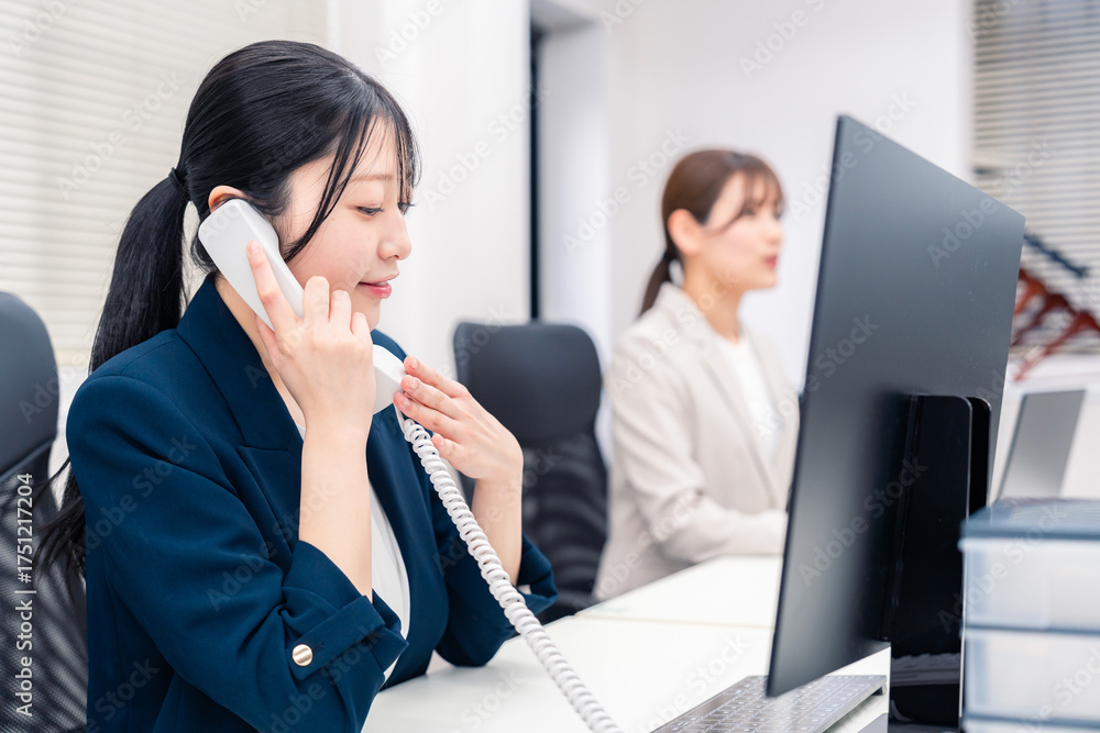 Fototapeta premium オフィスでにこやかに電話対応をするビジネスウーマン