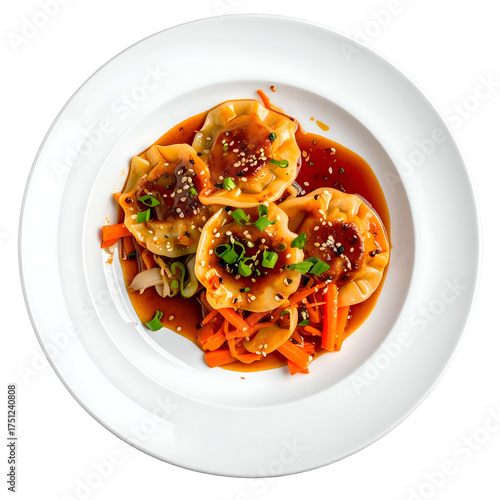 Overhead view of four dumplings with vegetables and sauce on a white plate
