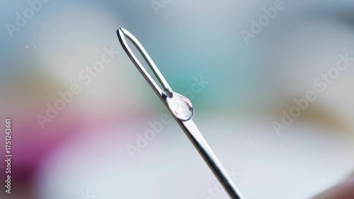 Close-up of a needle eye with water droplets on a blurred background