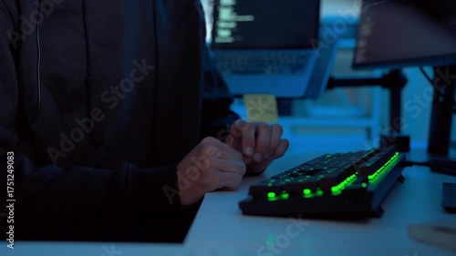 Close up shot focusing on programmer’s hands typing on illuminated keyboard for software development and database coding in IT department office during night shift, showing focus and precision.
