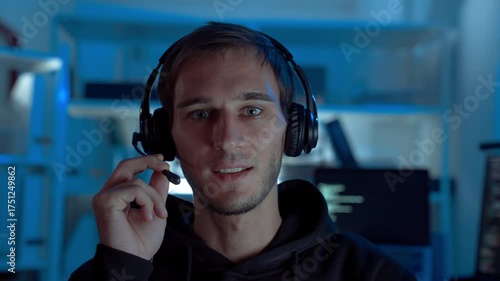 Professional IT support specialist wearing headset communicating with clients during night shift in call center office, showing reliability, remote assistance, and digital communication.