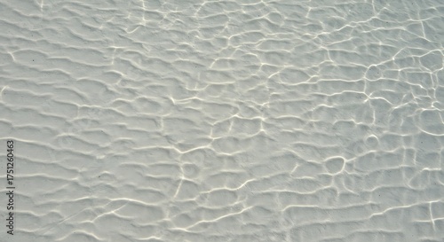Fototapeta Naklejka Na Ścianę i Meble -  An abstract view of shallow water with sunlight creating patterns on the sandy ocean floor surface