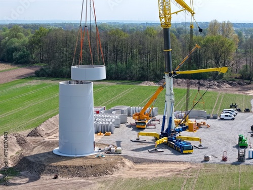 Großer Schwerlastkran setzt Teile für den Turm einer Windkraftanlage übereinander, Luftbild, Hochbau, Windenergie, Windrad, Aufbau, Kran, Energiewende, Nachhaltigkeit, Energie, regenerativ